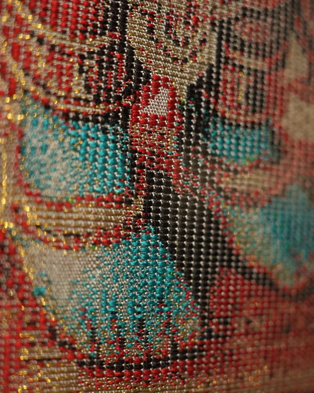 Close-up of the Srinivasa Kalyanam silk artwork, wedding guests woven in red and turquoise silk with gold zari